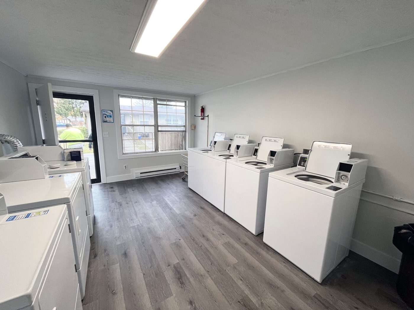 Renovated apartment community laundry room with new machines and plank flooring.