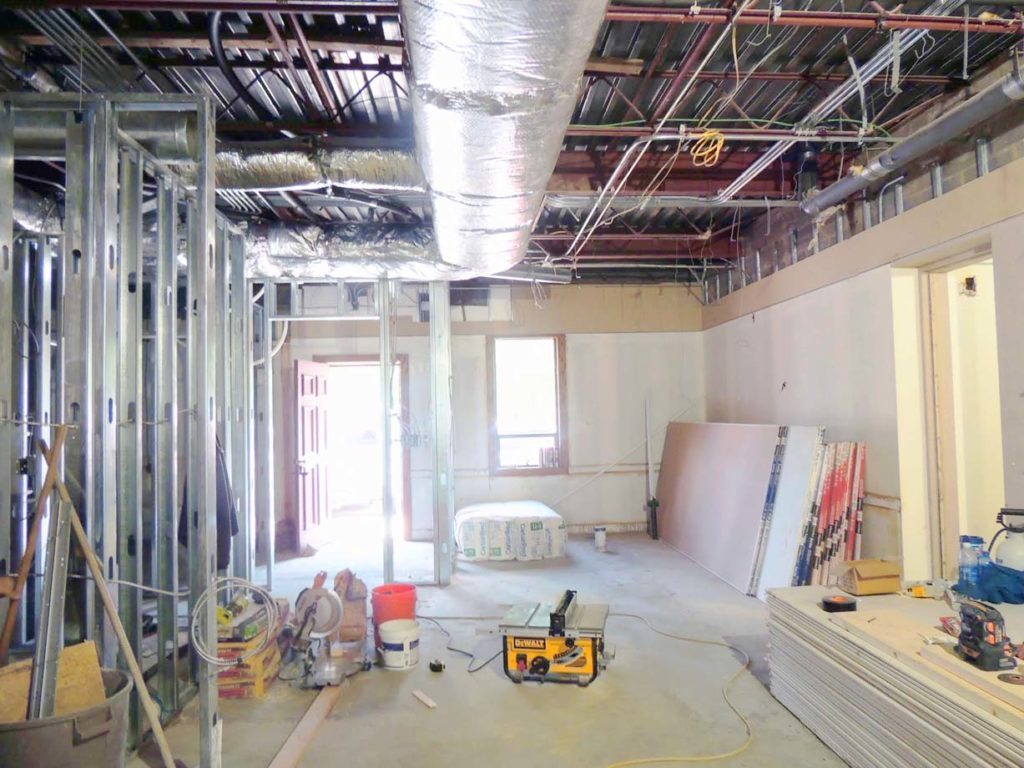 Interior of an apartment building stripped to steel stud framing and overhead mechanical runs during a gut renovation.