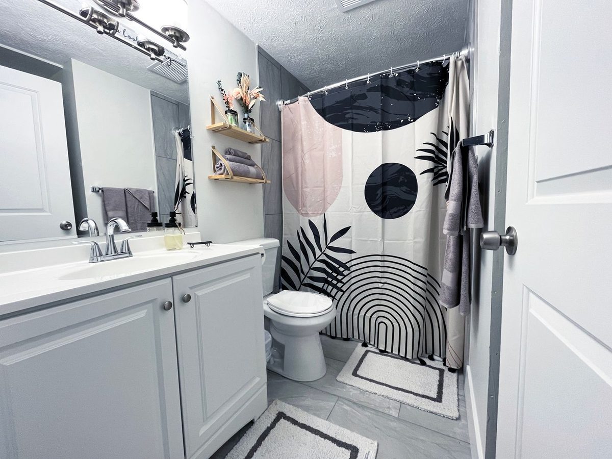 A renovated apartment bathroom with new vanity, mirror, lighting and tile.
