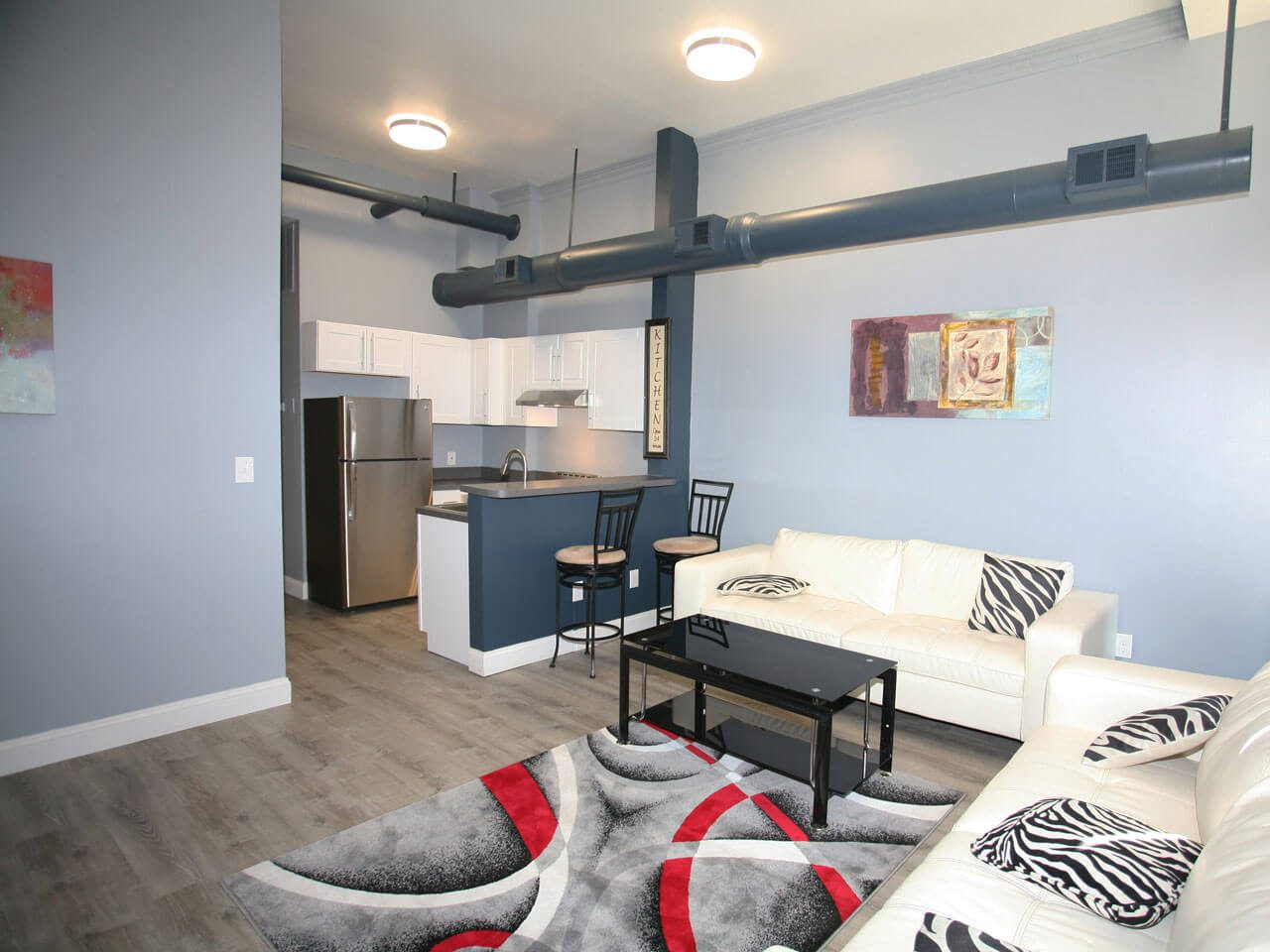 A loft apartment interior with exposed ductwork and open kitchen.